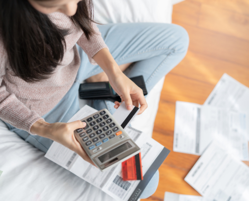 Woman sitting among a pile of unpaid bills